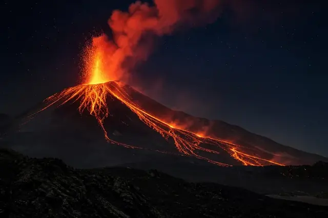 Volcanic eruption glowing orange beneath a starry night sky