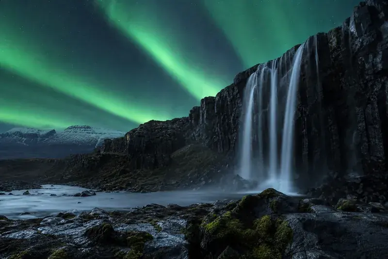Icelandic waterfall beneath a green aurora